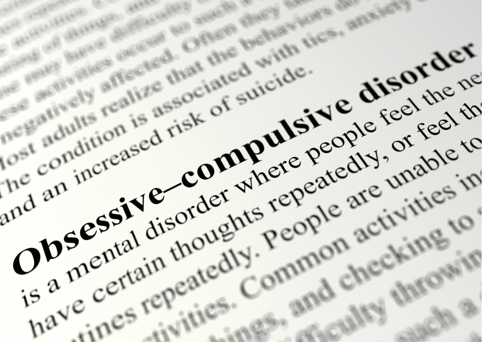 A close-up of a dictionary or textbook page highlighting the term "Obsessive–compulsive disorder" in bold, with the definition text visible around it.