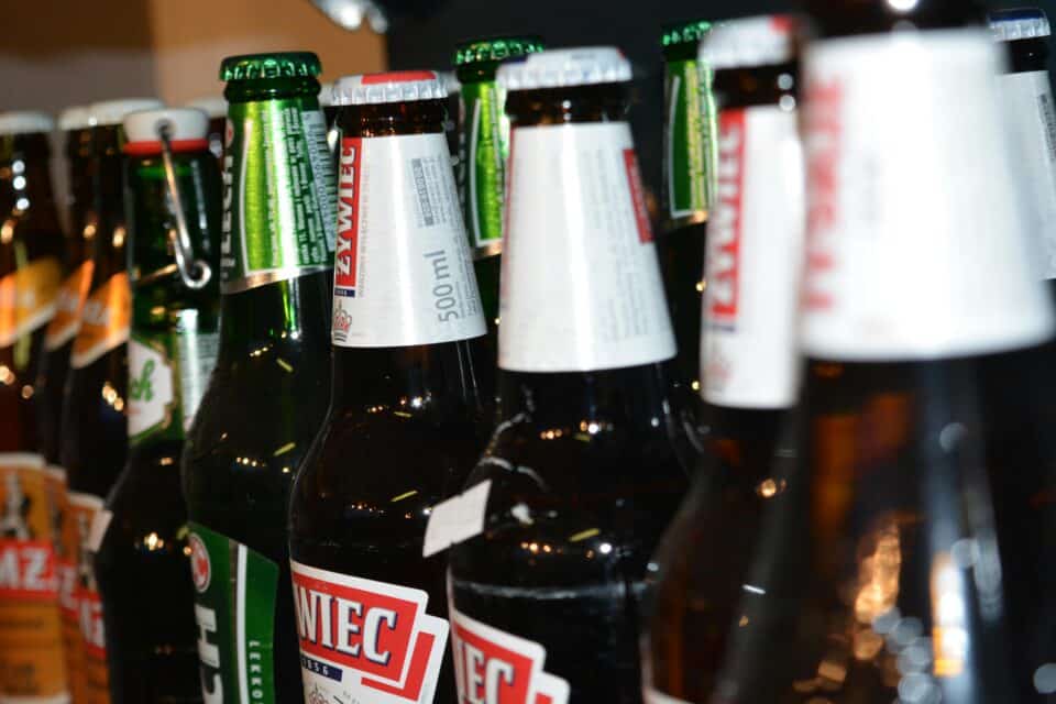 Close-up view of several beer bottles standing together, some with green glass and others brown, with caps still on and labels visible.