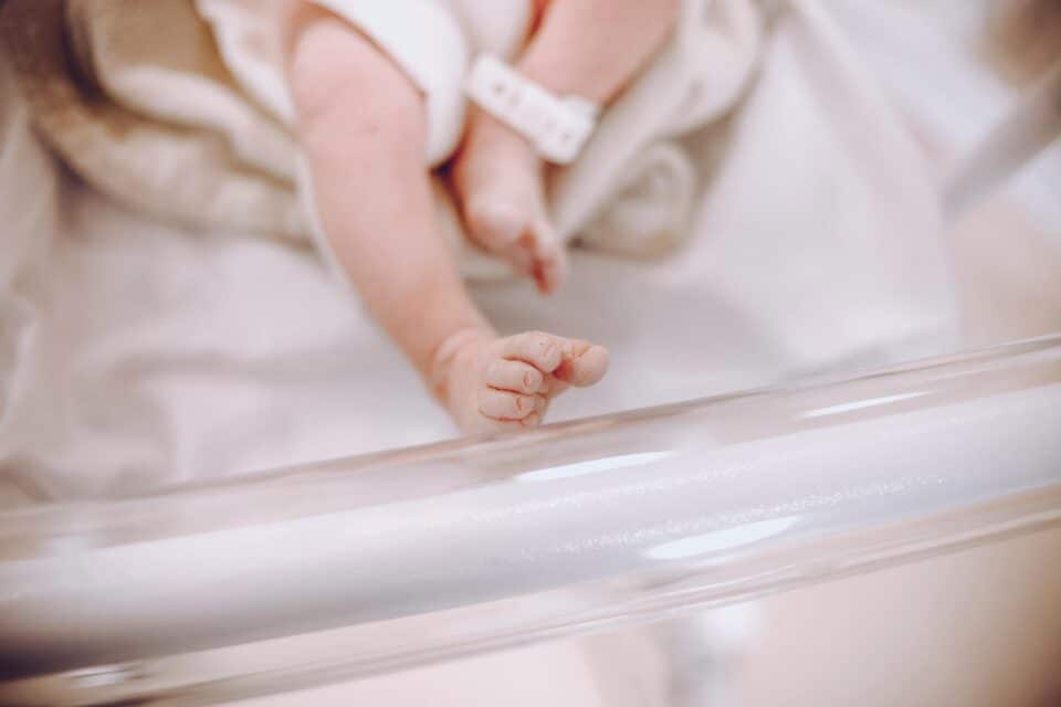 Close-up of a newborn baby's tiny foot in a hospital crib.
