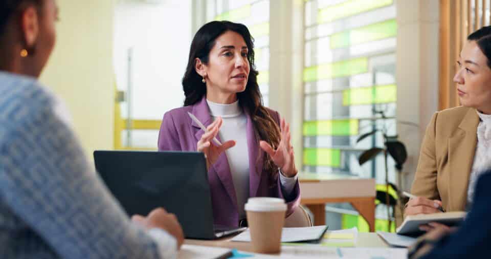 A professional woman speaking during a meeting, representing leadership, communication, and collaboration in the workplace.