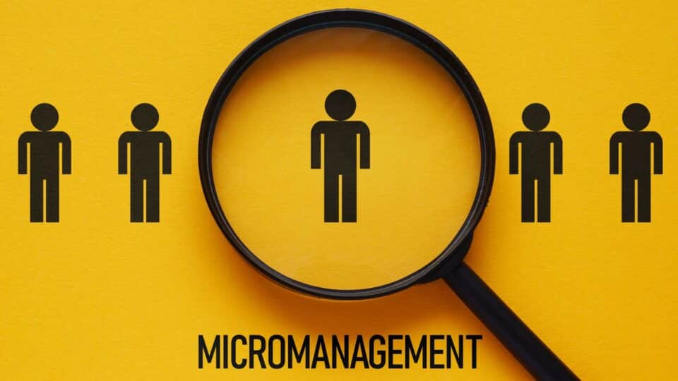 Illustration of a magnifying glass focusing on one person among others, representing micromanagement.
