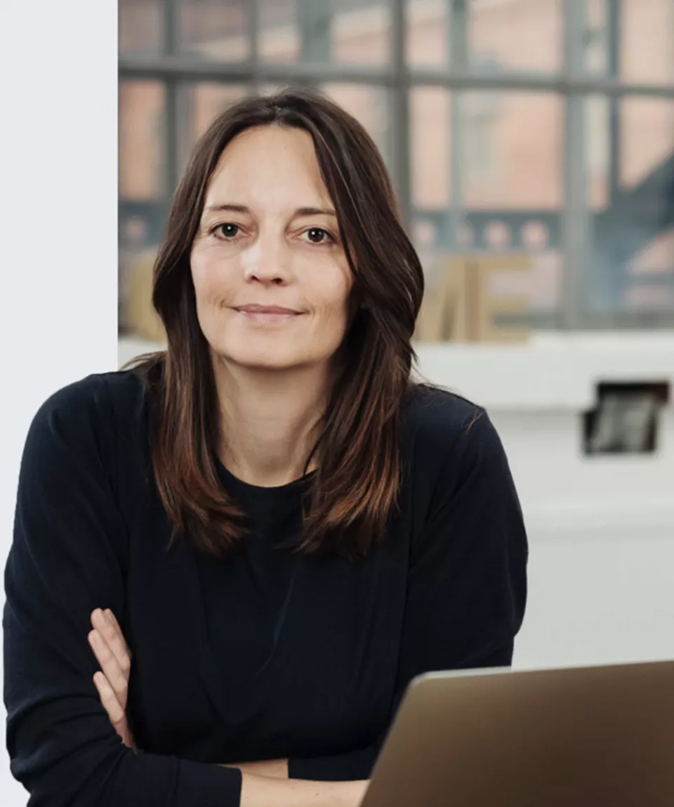 Woman in an office next to a laptop looking at the camera