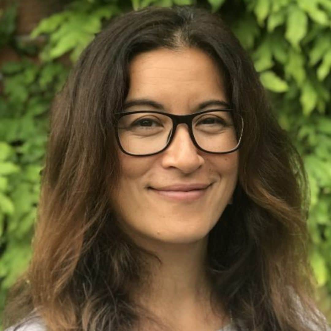 Woman with long dark hair and glasses smiling