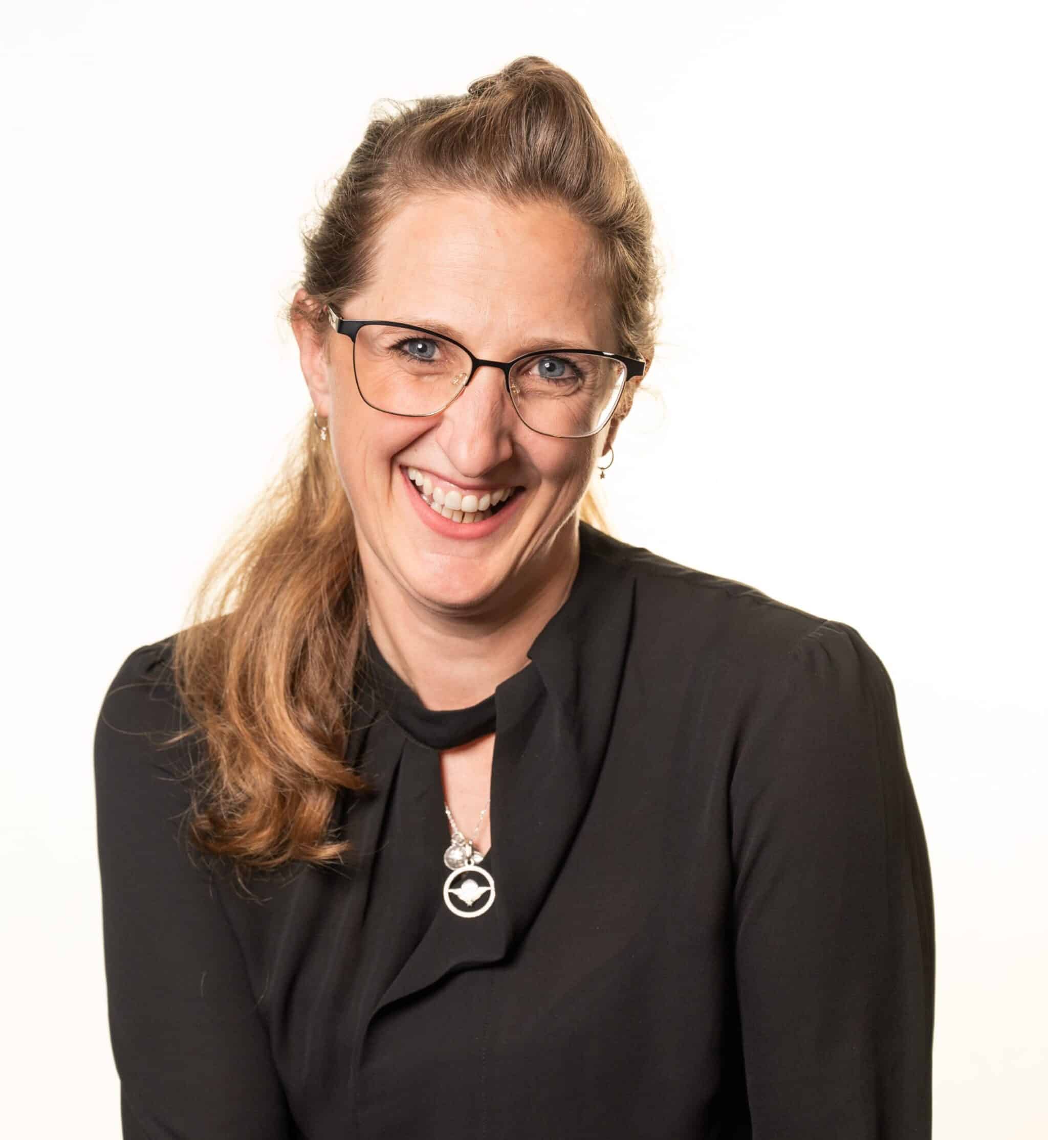 Woman with glasses in smart black clothes smiling