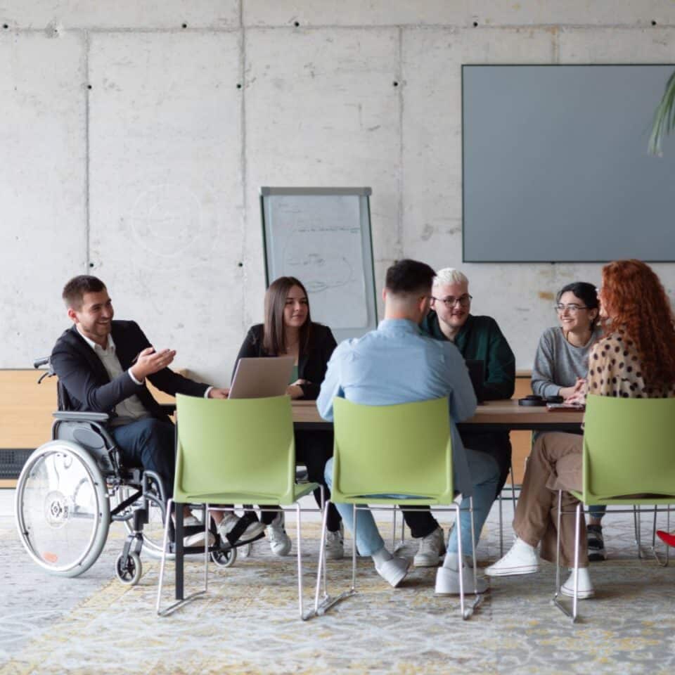 Diverse group of people in an office meeting around a large table.