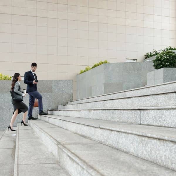 Two business professionals walking up a wide set of outdoor steps while talking.
