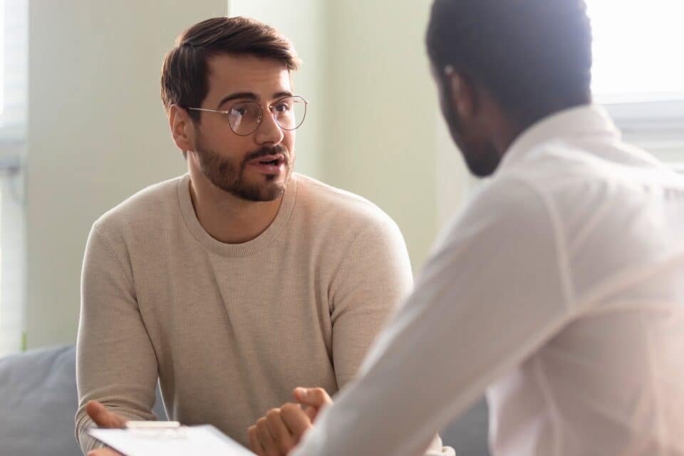 Young man with glasses talking with a colleague