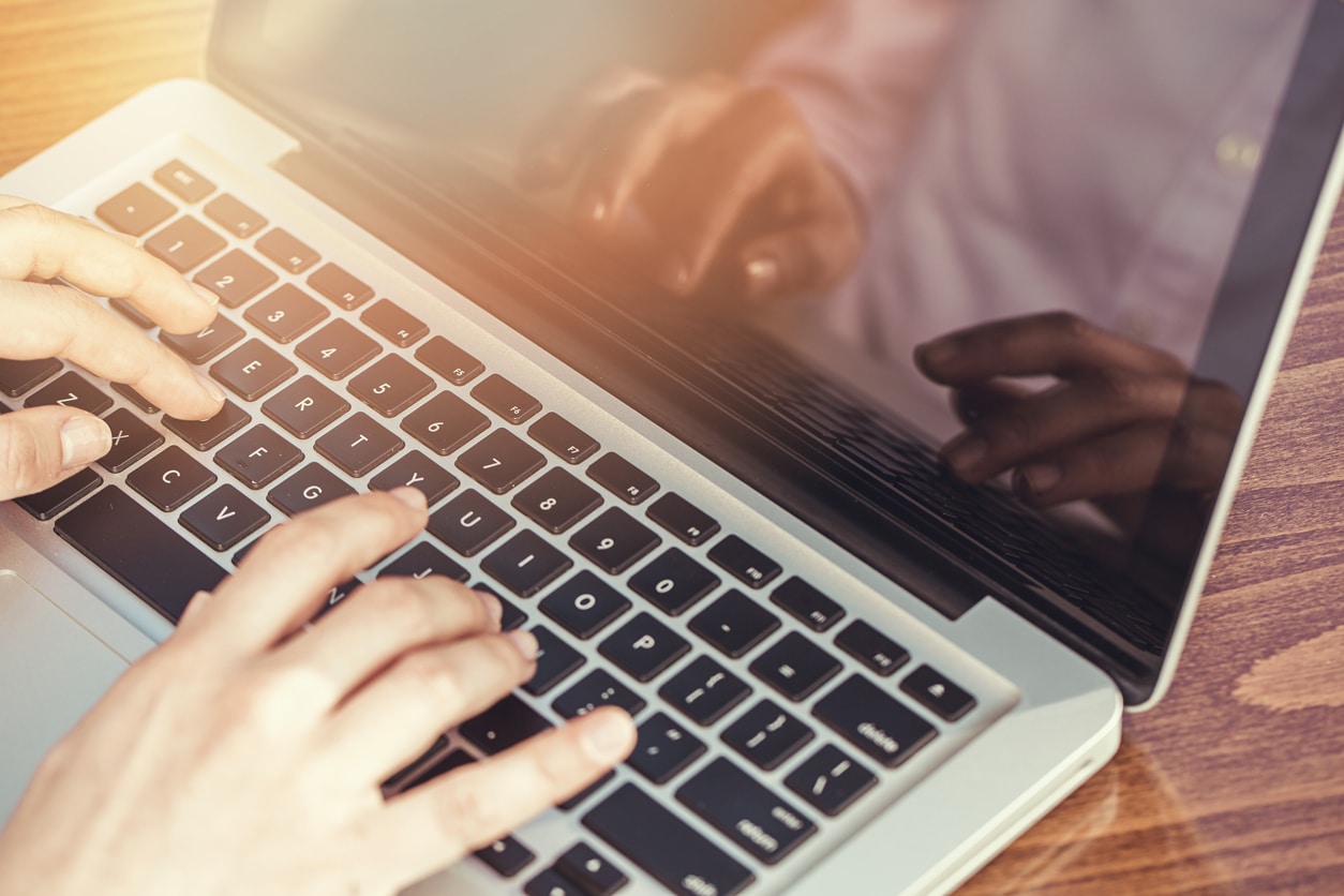 Hands typing on a laptop keyboard