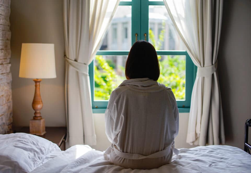 Woman sat in bed looking out of window