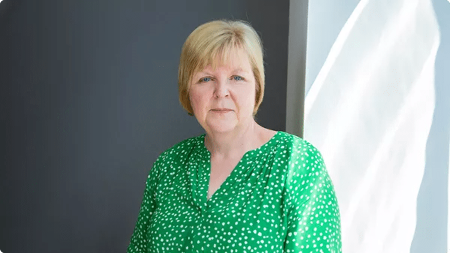 Woman in green top with short blonde hair.