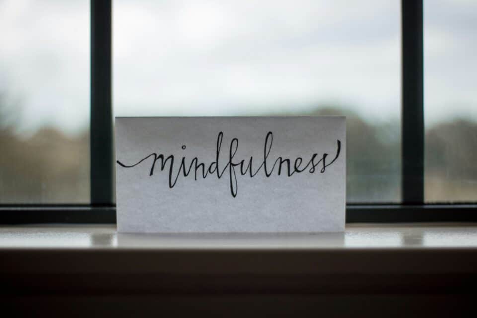 Card with the word ‘mindfulness’ written in calligraphy, placed on a windowsill.