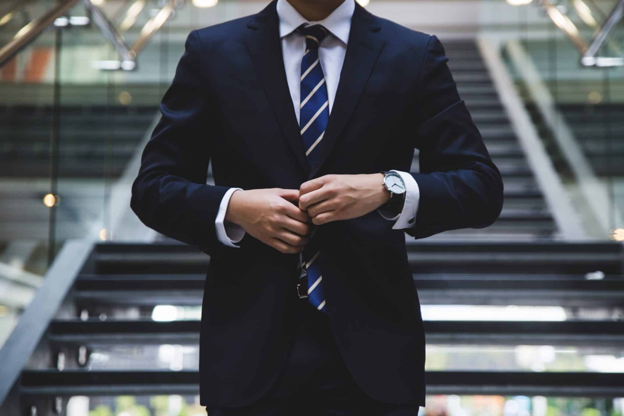 Man in suit and tie at the bottom of some stairs in an office