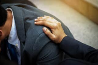 Close-up of a hand placed on a person’s shoulder, offering comfort and support
