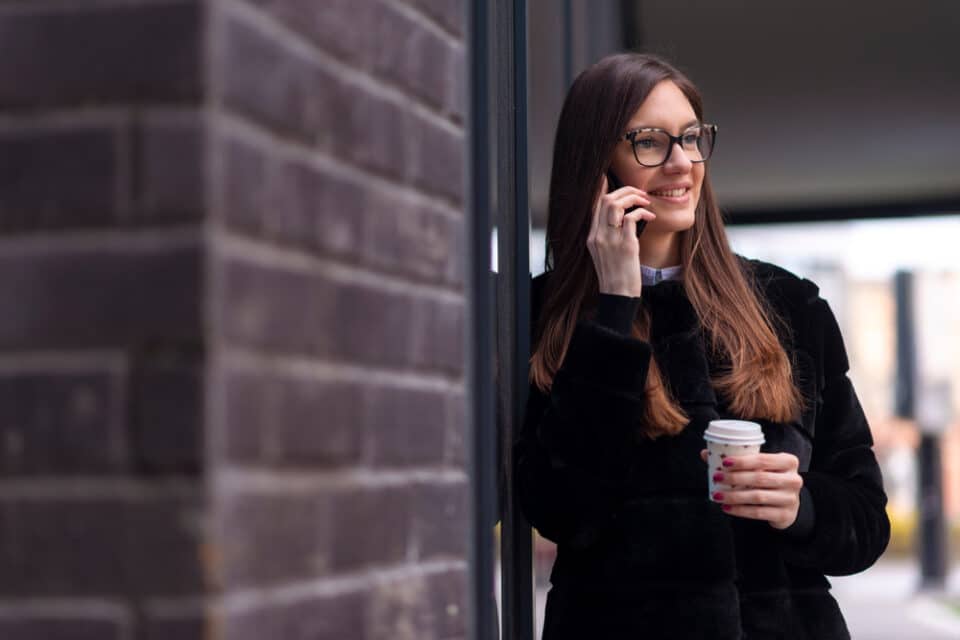 Young woman on the phone holding a coffee
