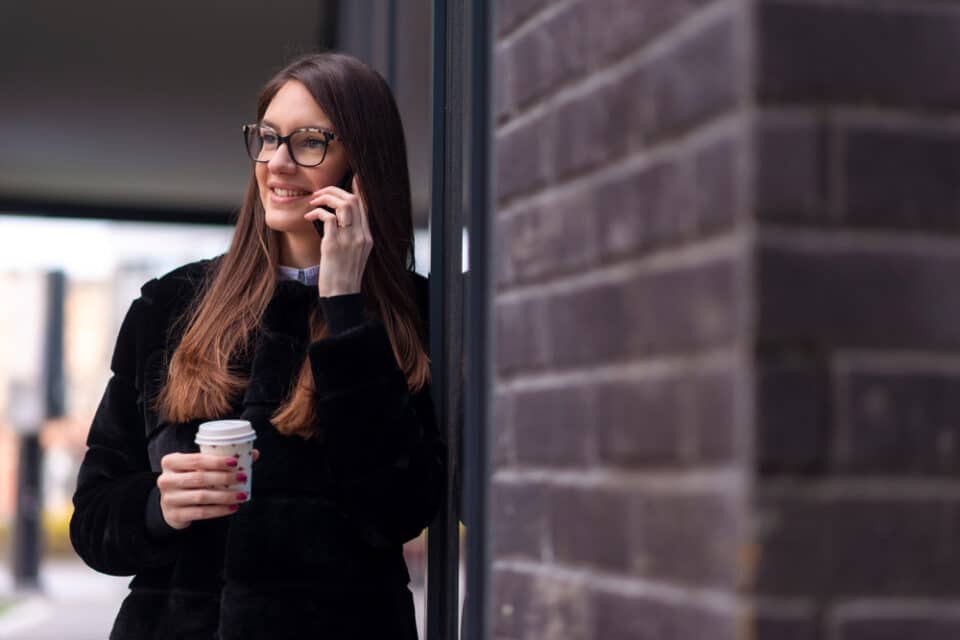 Young woman on the phone holding a coffee