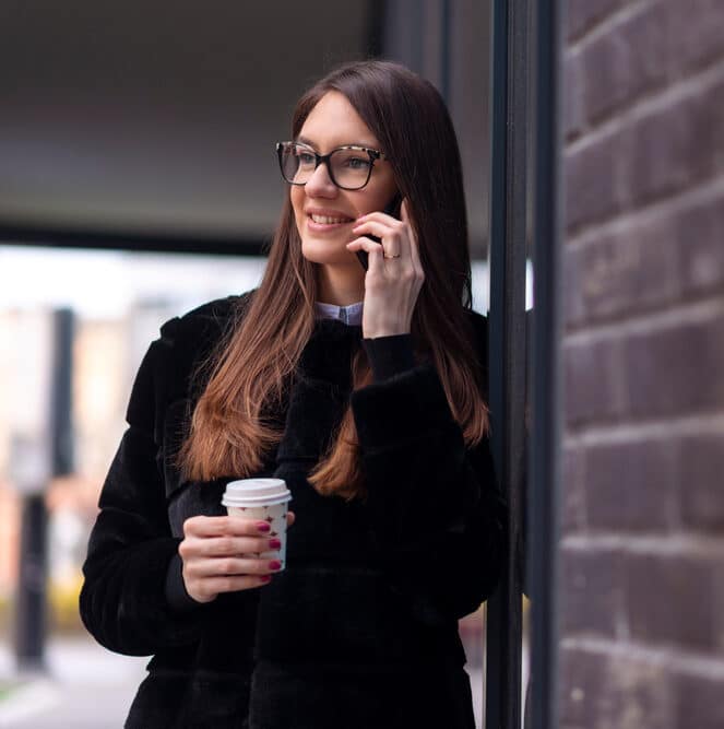 Young woman on the phone holding a coffee