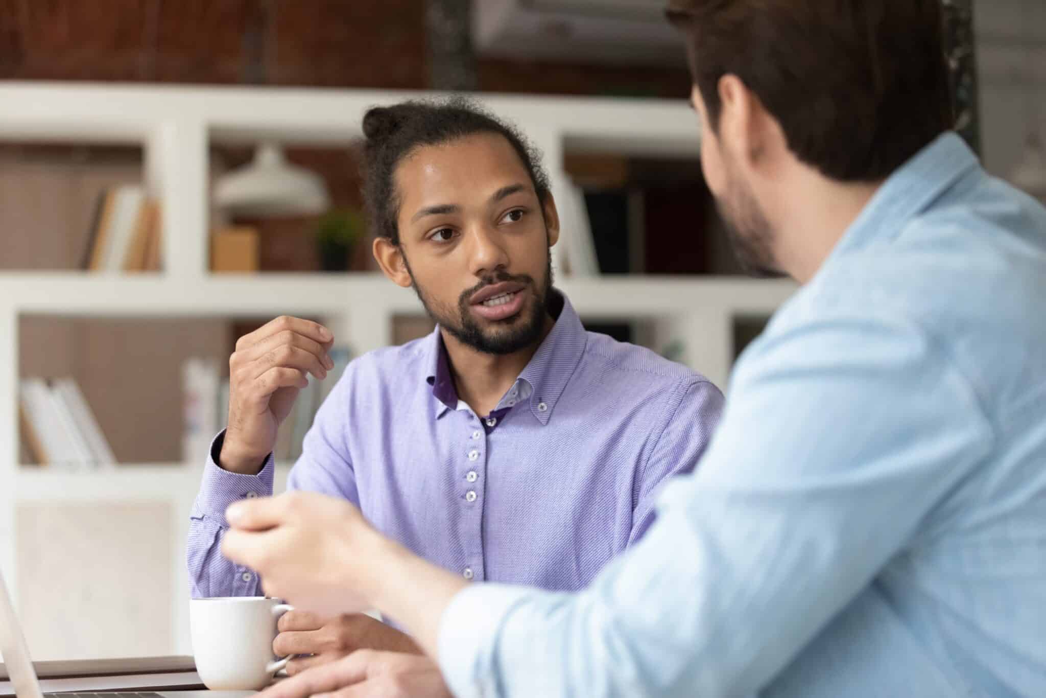 Young man in shirt in conversation with a collegaue.