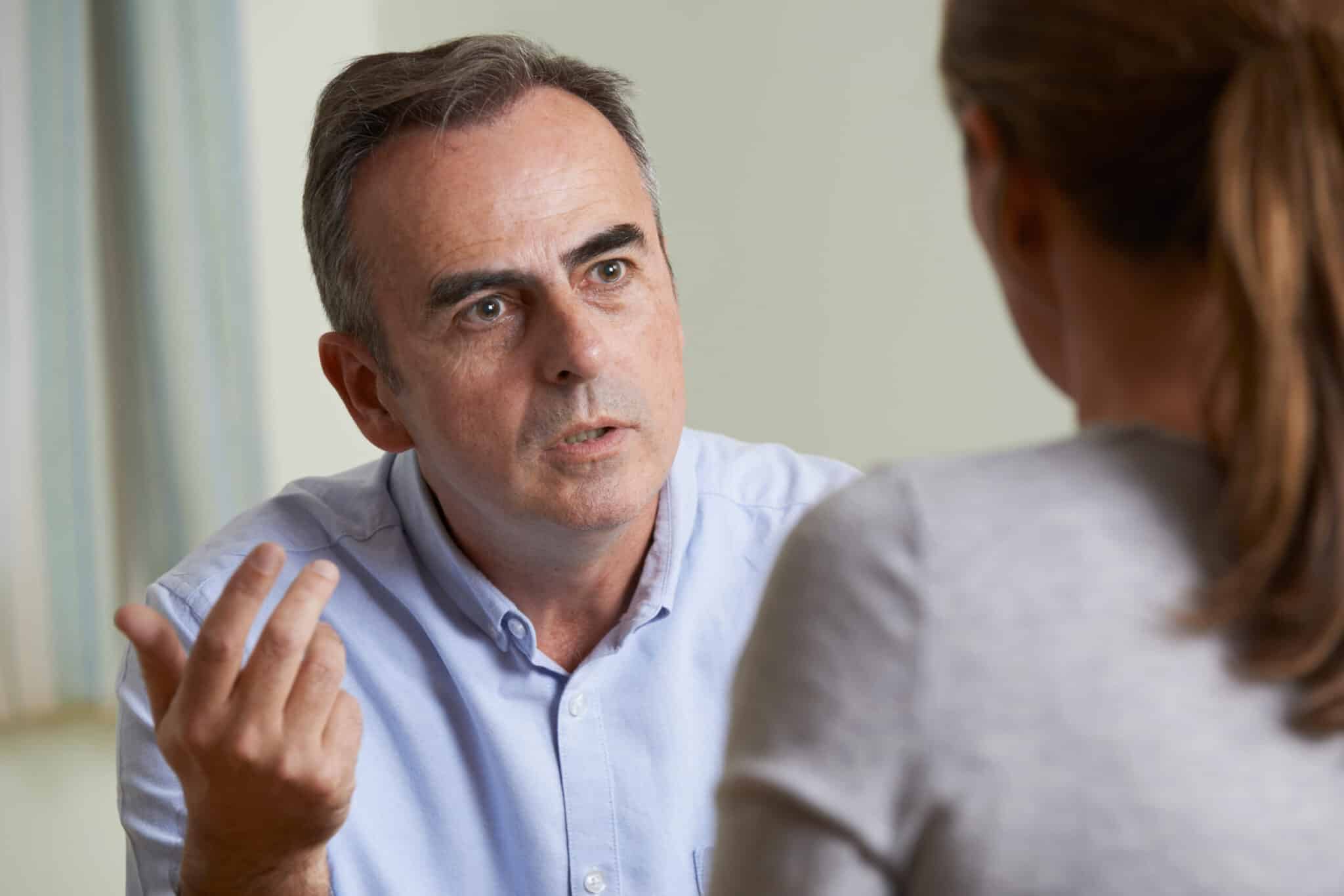 Middle-aged man talking seriously to a woman during a one-to-one conversation.