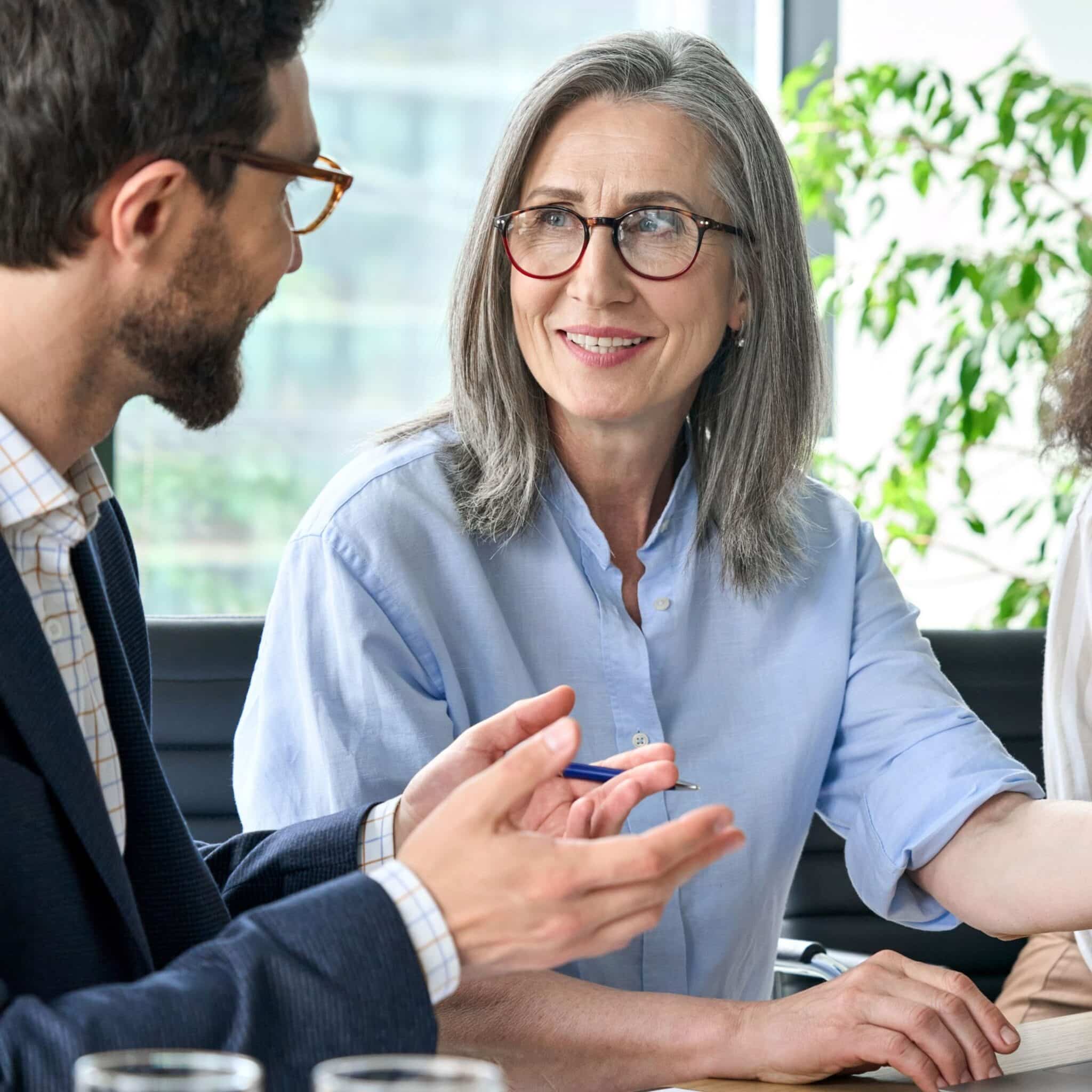 Smiling professional woman talking with a colleague during a meeting in a modern office.