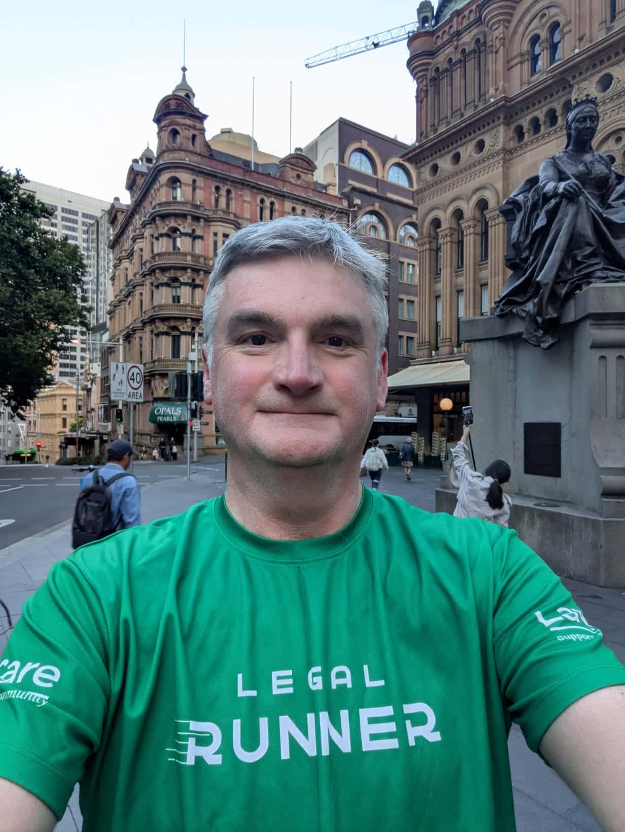 Mark Evans wearing a green ‘Legal Runner’ top, with city buildings in the background.