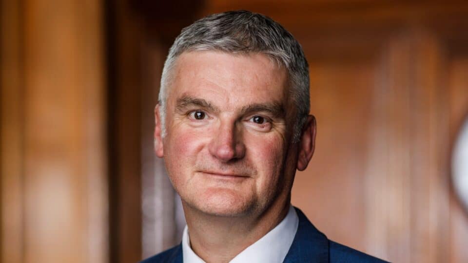 Portrait of Mark Evans, wearing a suit and tie, photographed indoors.
