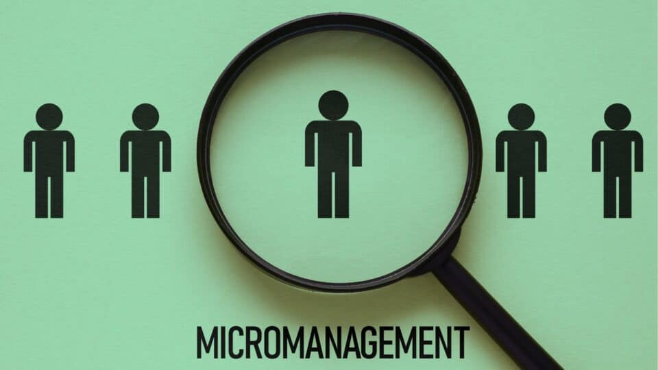 Illustration of a magnifying glass focusing on one person among others, representing micromanagement.