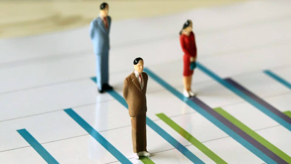 Image showing small figurines of professionals standing on chart lines to represent performance or expectations.
