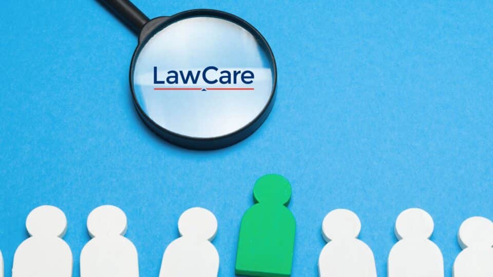 Magnifying glass highlighting the LawCare logo above a row of figures, with one figure shown in green to represent a job opportunity or recruitment.
