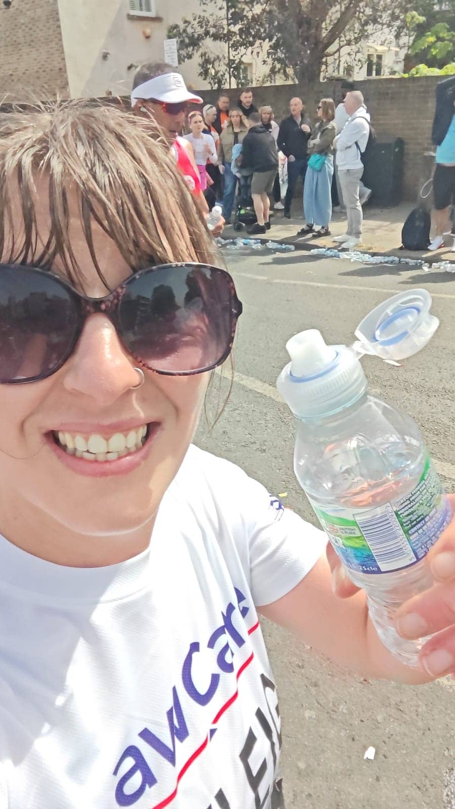 Kayleigh running past (mid race) and having a quick drink of water. She is wearing a LawCare t-shirt.