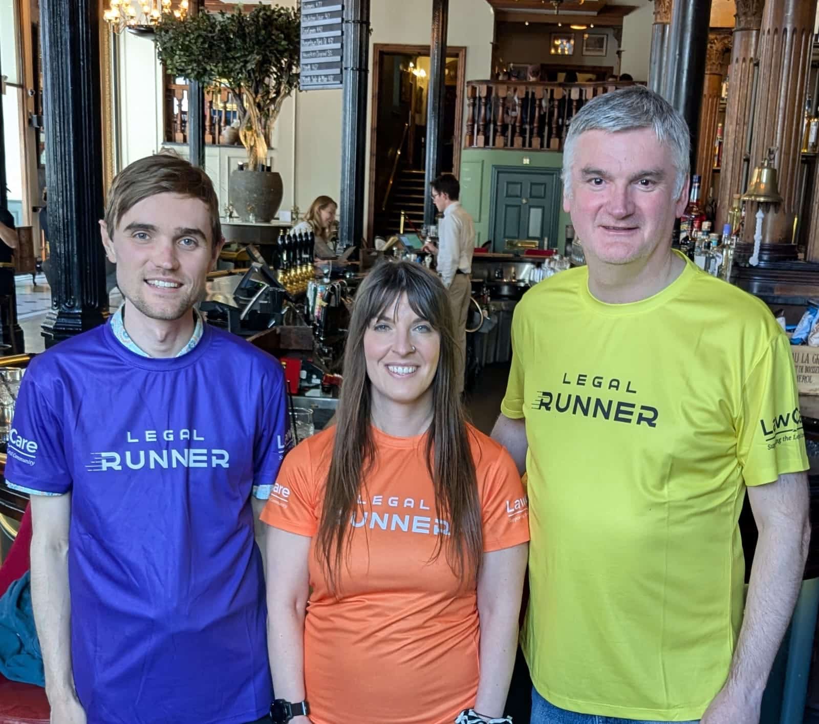 All three runners. Matt wearing a blue Legal Runner t-shirt, Kayleigh in the centre wearing an orange  Legal Runner t-shirt, and Mark on the right wearing a yellow  Legal Runner t-shirt.