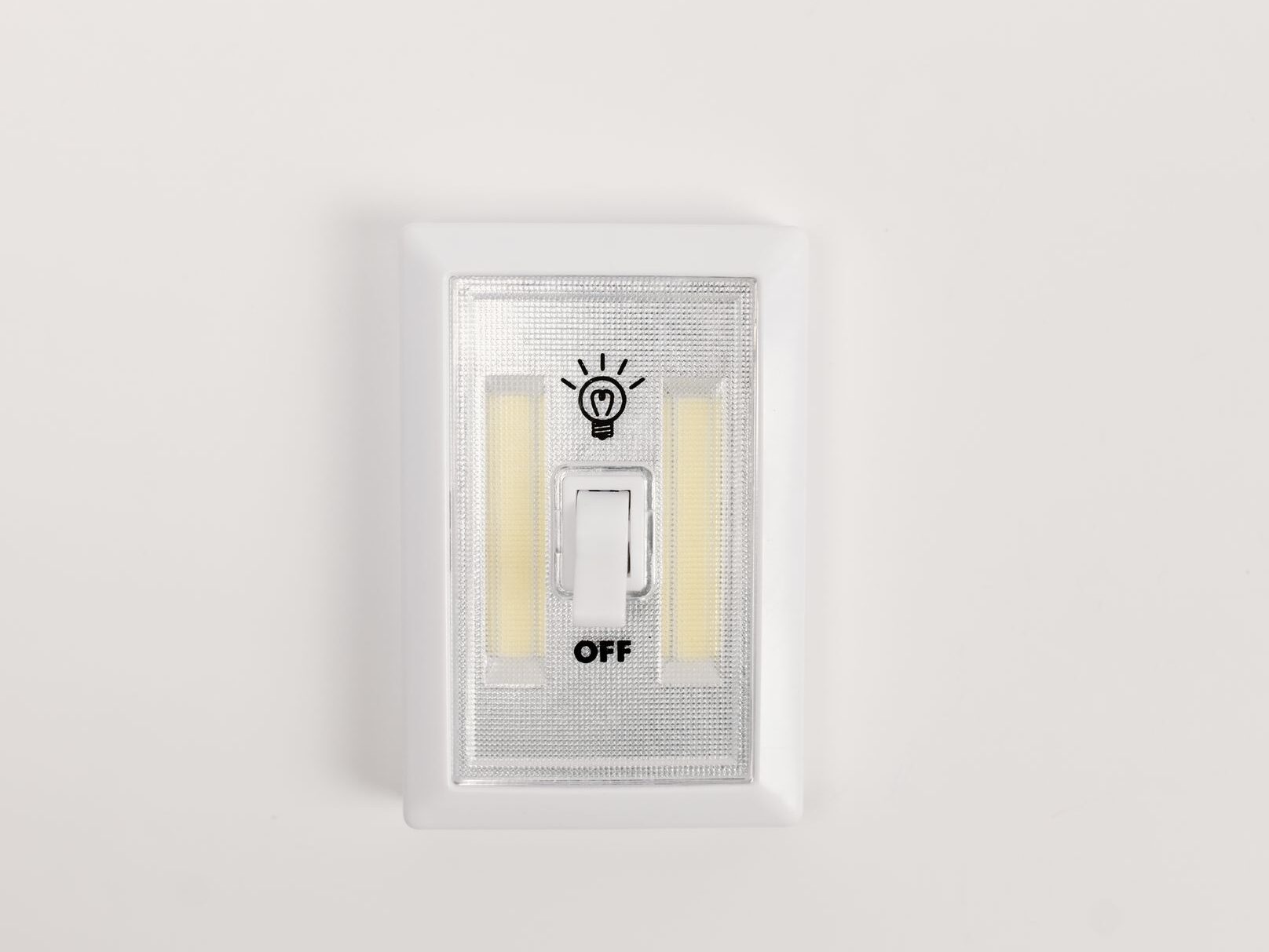 Close-up of a white light switch on a plain wall, set to the "off" position beneath a lightbulb icon. The image symbolises switching off, taking a break or disconnecting from work.