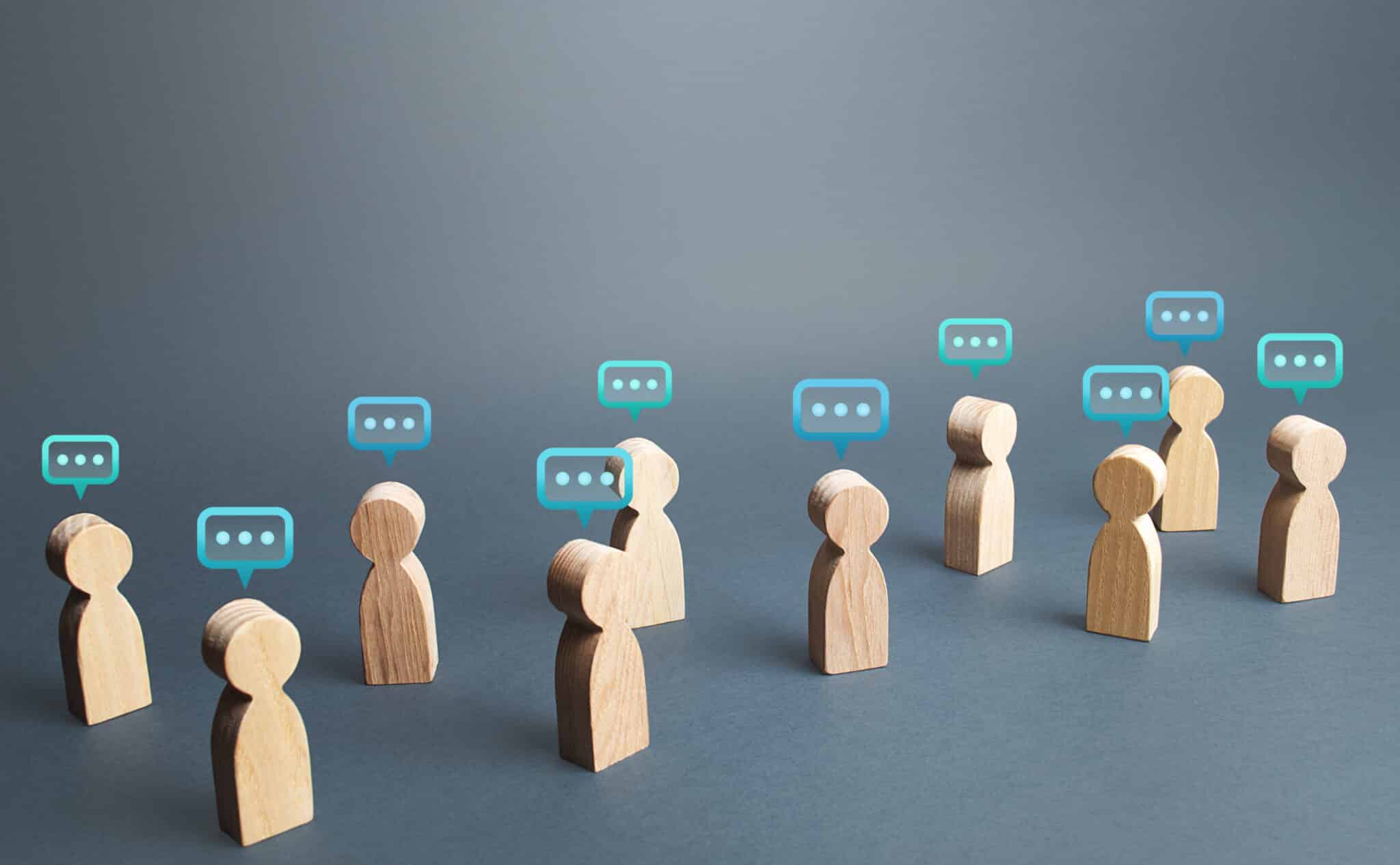 wooden figures standing apart, each with a speech bubble above them, against a blue background.