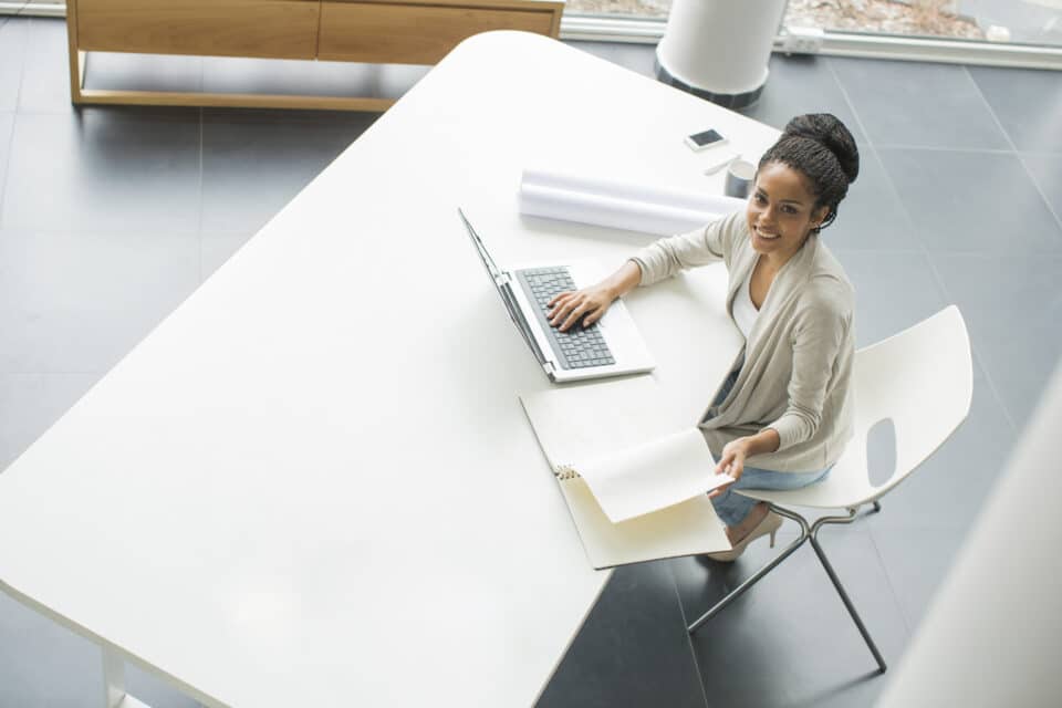 Young woman sat at desk, smiling and looking up