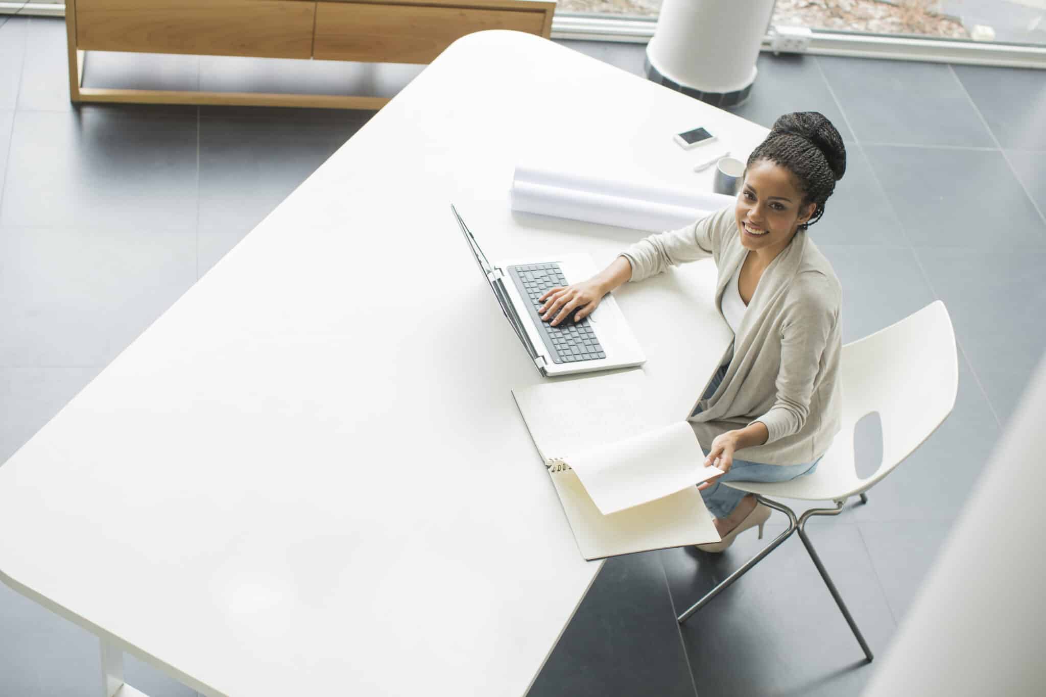 Young woman sat at desk, smiling and looking up